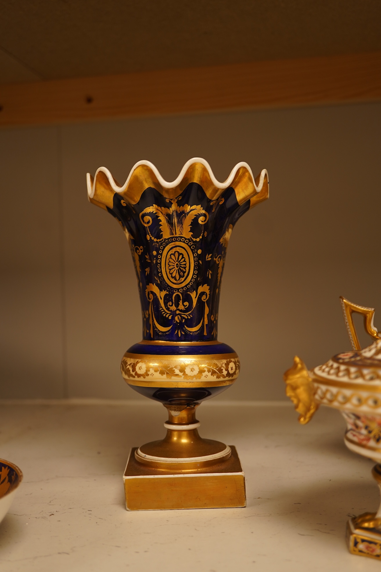 A collection of Royal Crown Derby, to include a two handled bowl, a fluted pedestal vase, saucer with landscape central cartouche etc (5). Vase 19cm high.